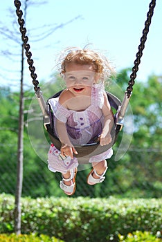 Happy girl laughs as she swings at the park