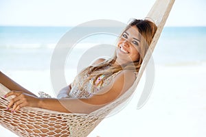 Happy girl laying in a hammock at the beach