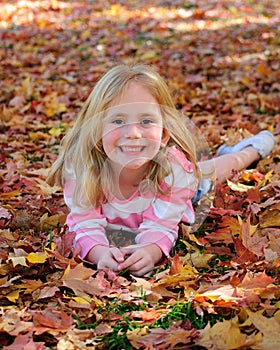 Happy girl laying in leaves