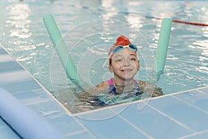 Happy girl learning to swim with pool noodle