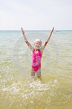 Happy girl let up splashes water standing