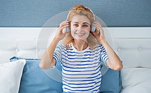 Happy girl listening to music on bed, leisure. Woman enjoying leisure pastime at home