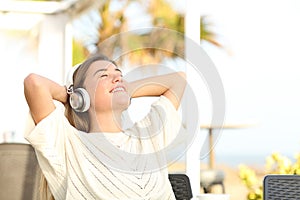 Happy girl listening to music resting in a terrace on the beach