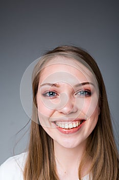 Happy girl with long hair smiling broadly showing snow-white teeth and looking at the camera photo