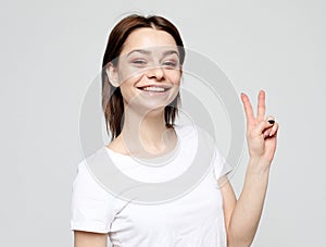 Happy girl looking at camera with smile and showing peace sign with fingers