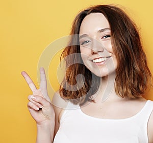 Happy girl looking at camera with smile and showing peace sign with fingers
