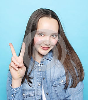 Happy girl looking at camera with smile and showing peace sign with fingers