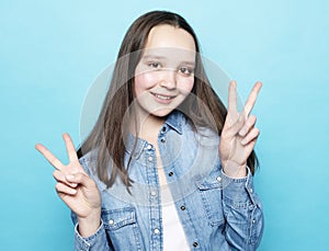 Happy girl looking at camera with smile and showing peace sign with fingers