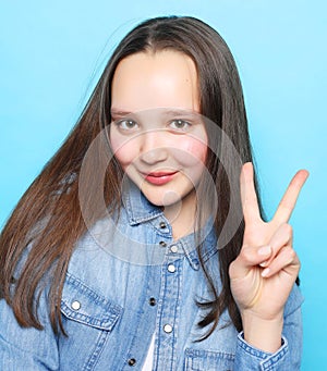 Happy girl looking at camera with smile and showing peace sign with fingers