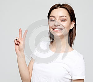 Happy girl looking at camera with smile and showing peace sign with fingers