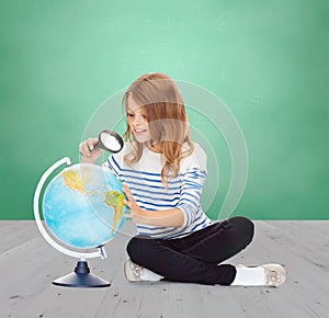 Happy girl looking at globe with magnifier