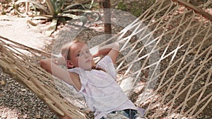 Happy girl lying in hammock at summer day. Smiling girl relaxing in hammock while summer vacation.