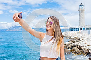 Happy girl making selfie in front of Patras lighthouse, Peloponnese, Greece.