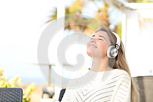 Happy girl meditating listening to music in a coffee shop