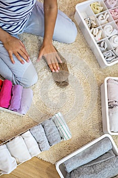 Happy girl neatly roll folded underwear and socks in plastic container box Marie Kondo method