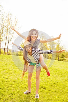 Happy girl piggybacking her friend and gesturing like an airplane