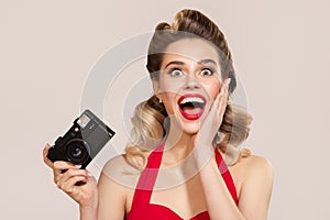 Happy girl in pin-up style holds retro camera in her hand