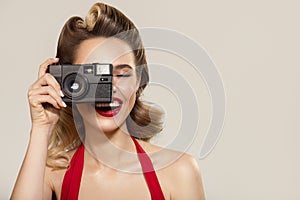 Happy girl in pin-up style holds retro camera in her hand