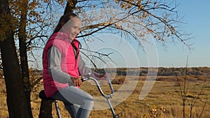 Happy girl in pink jacket rides bicycle in autumn park. hands of girl hold the bent handlebar.