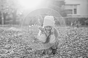 Happy girl playing with autumn leaves. Happy child walking and having fun in fall backyard