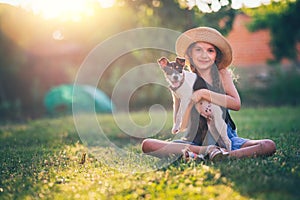 Happy girl playing with cute playful puppy little dog outdoor on a sunny day in a park