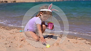 Happy girl playing with easter eggs on the beach