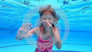 Happy girl playing in outdoor swimming pool on summer vacation on tropical beach.