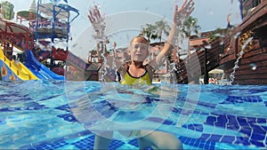 Happy girl playing in outdoor swimming pool on summer vacation on tropical beach.