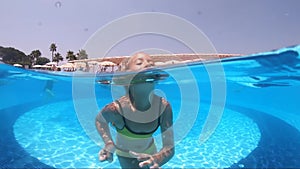 Happy girl playing in outdoor swimming pool on summer vacation on tropical beach.