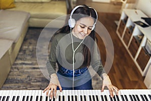 Happy girl is playing piano for her hobby relax time in home living room.