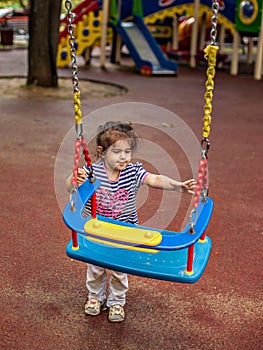 Happy girl playing on the swing on the Playground