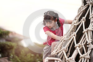 Happy girl playing on a tightrope in a playground