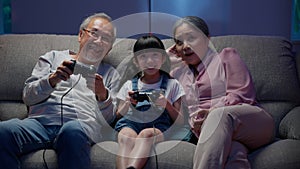 Happy girl playing video games with senior grandparents happily