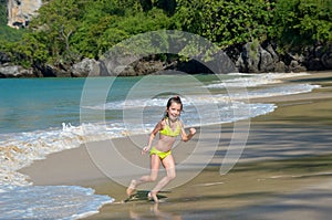 Happy girl plays in sea on tropical beach