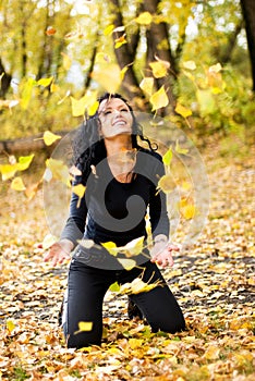 Happy girl pleying with yellow leaves