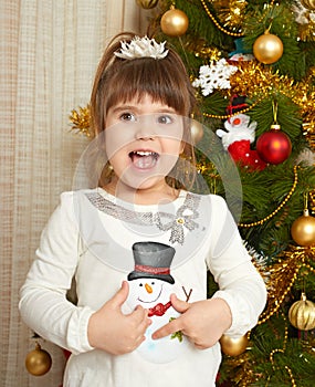 Happy girl portrait in christmas decoration, playing with snowman toy, winter holiday concept, decorated fir tree and gifts