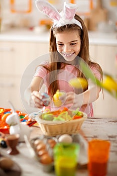 Girl preparing Easter basket with colorful eggs