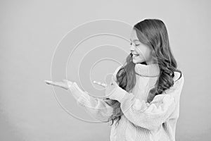 Happy girl present product on blue background. Pure beauty of baby girl. Small girl with long hair. knitting for kids