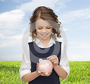 Happy girl putting coin into piggy bank