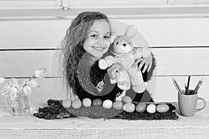 Happy girl with rabbit toy, pencil, tulip flowers, easter eggs