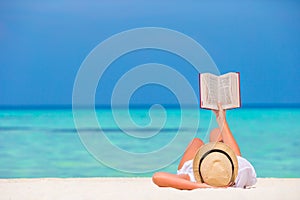 Happy girl reading during tropical white beach