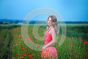 Happy girl in a red dress on poppy field