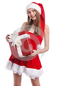Happy girl in red dress and santa hat holding a gift box and smiling sweetly. Isolated.