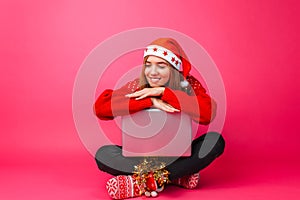 Happy girl in a red sweater and Santa hat, sitting with a laptop