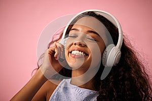 Happy girl, relax and listening to music with headphones for jazz or beats on a pink studio background. Female person