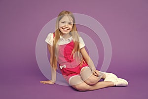 Happy girl relax on violet background. Beauty and fashion look. Little child with smile on cute face, beauty. Fashion