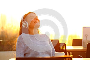 Happy girl relaxing listening to music in a terrace at sunset