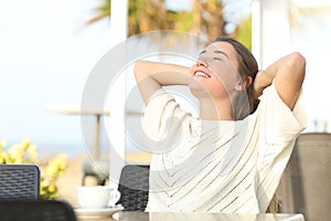 Happy girl relaxing sitting in a terrace on the beach