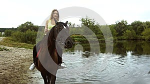 Happy girl rides a horse on the Lake