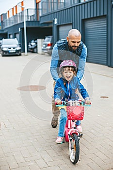 Happy girl riding a bike with her father\'s hepl.